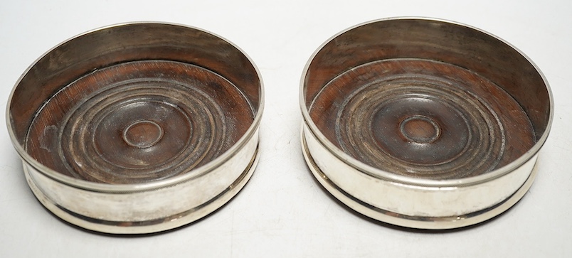 A pair of 19th century Continental white metal wine coasters, inset with turned mahogany bases, 12.5cm diameter. Condition - fair